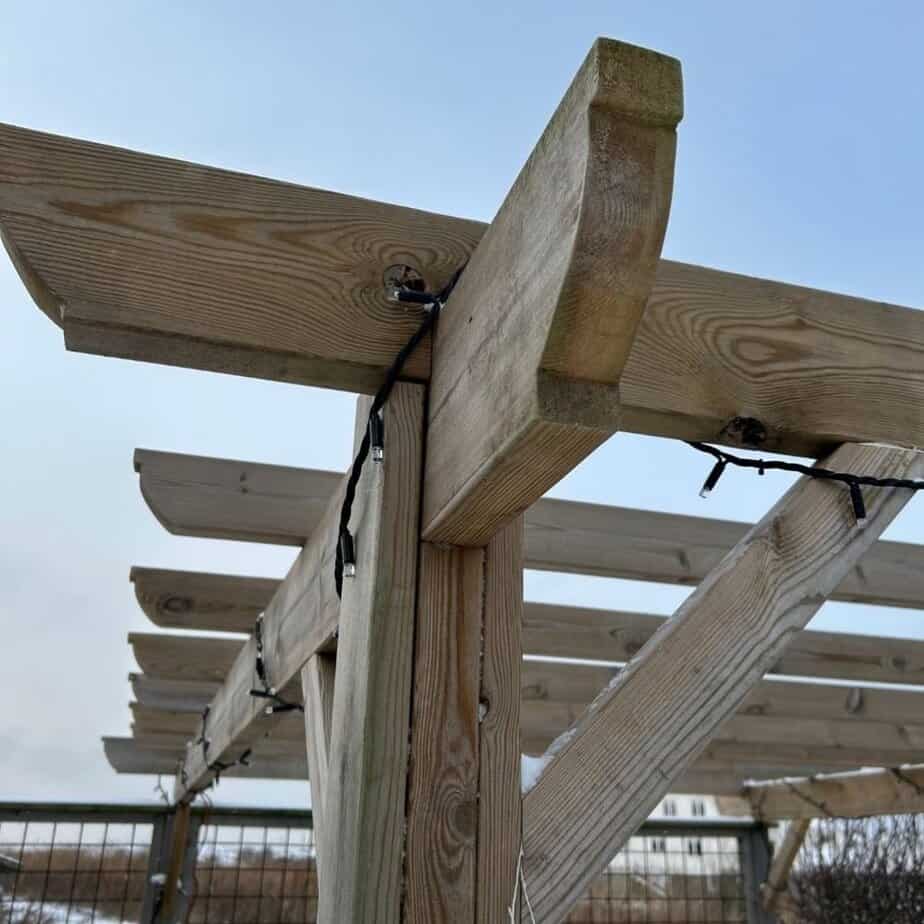 Rostfria krokar och beslag monterade i pergolabalk för upphängning av solsegel.